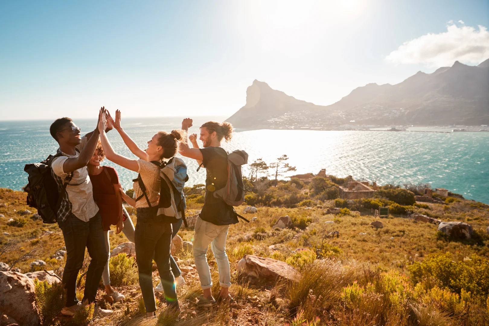 Group of millennial travelers celebrating an excursion by the sea, an example of experiential and sustainable tourism.