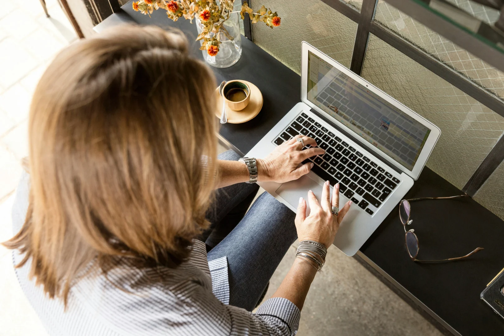 Profesional del sector turístico trabajando en su estrategia de captación B2B en LinkedIn desde un portátil, con café y gafas sobre la mesa.