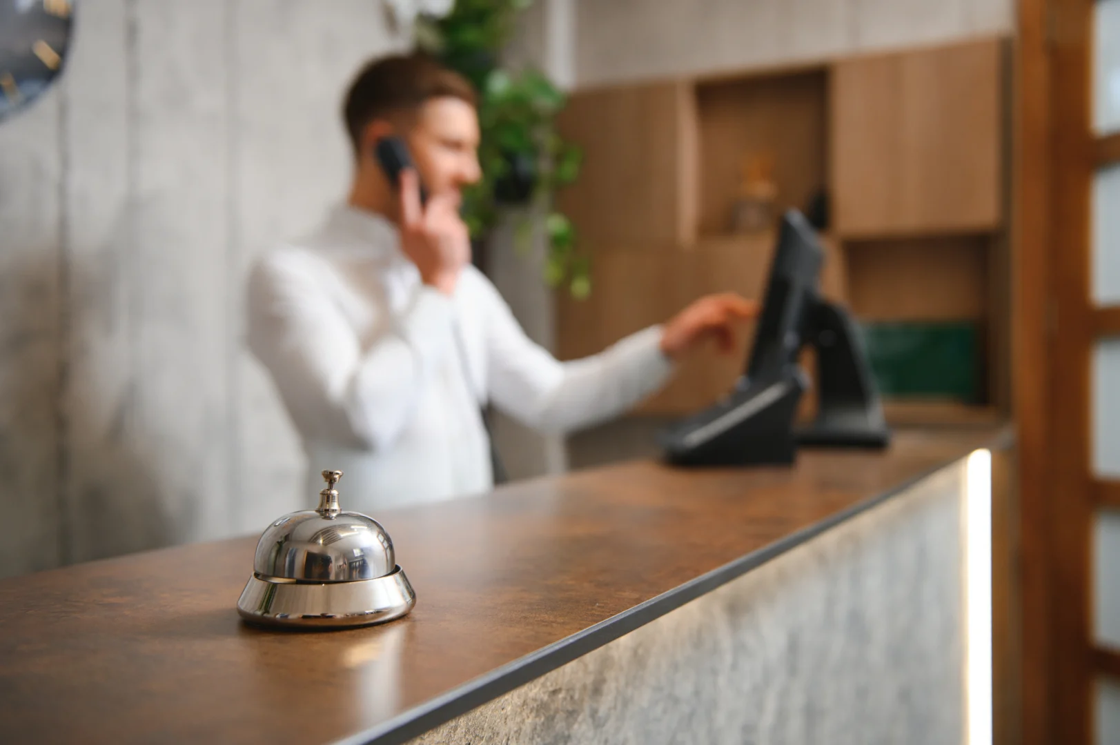 Recepcionista de hotel atendiendo una llamada en el mostrador de recepción